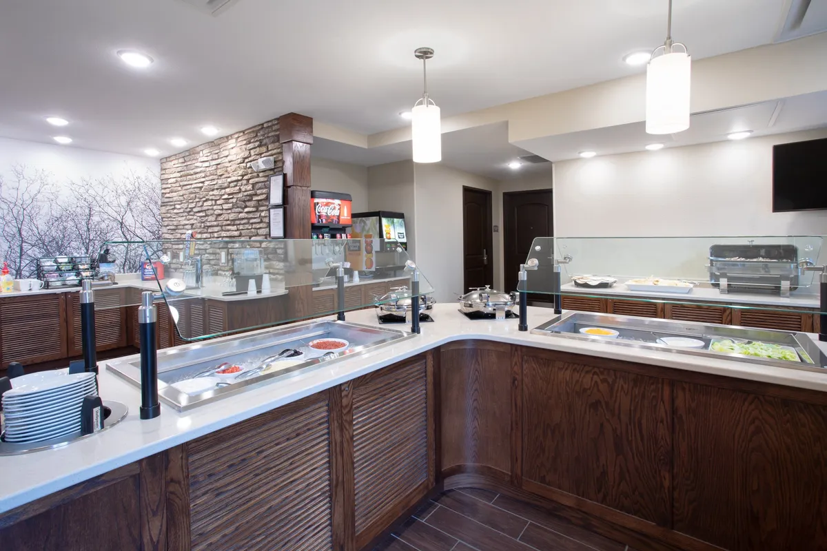 A vibrant buffet area featuring a variety of food options, spacious seating, and a stylish stone accent wall. The scene is set for casual dining and social gatherings, echoing the spirit of shared meals and culinary exploration.