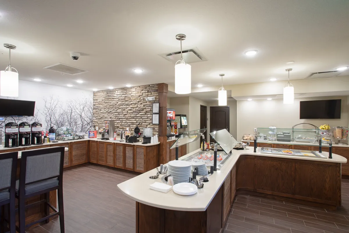 A welcoming breakfast buffet area with a coffee station, comfortable seating, and a decorative stone wall. The setup is ideal for enjoying the complimentary breakfast or a casual morning coffee, as mentioned in the section content.