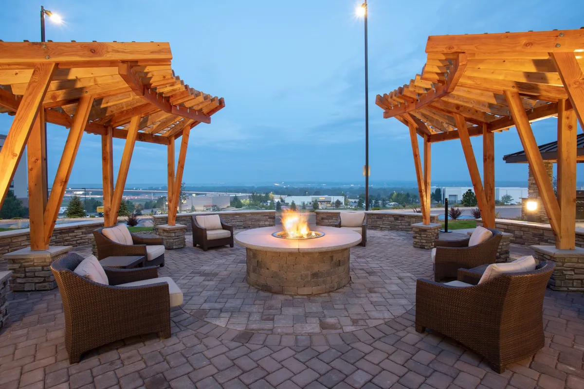 A cozy fire pit area with wooden pergolas and wicker chairs arranged for group gatherings. The ambiance is warm and inviting, ideal for evening relaxation, storytelling, or unwinding after a busy day of exploring local attractions.