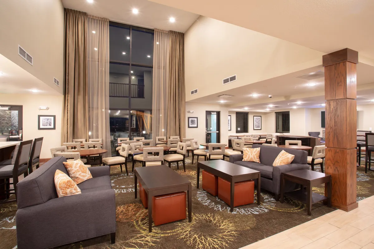 A welcoming living area with comfortable seating beneath large windows, modern décor accents, and a relaxed atmosphere ideal for socializing, watching TV, or working remotely. The space is bathed in natural light, with thoughtfully arranged furniture for gatherings or personal downtime.