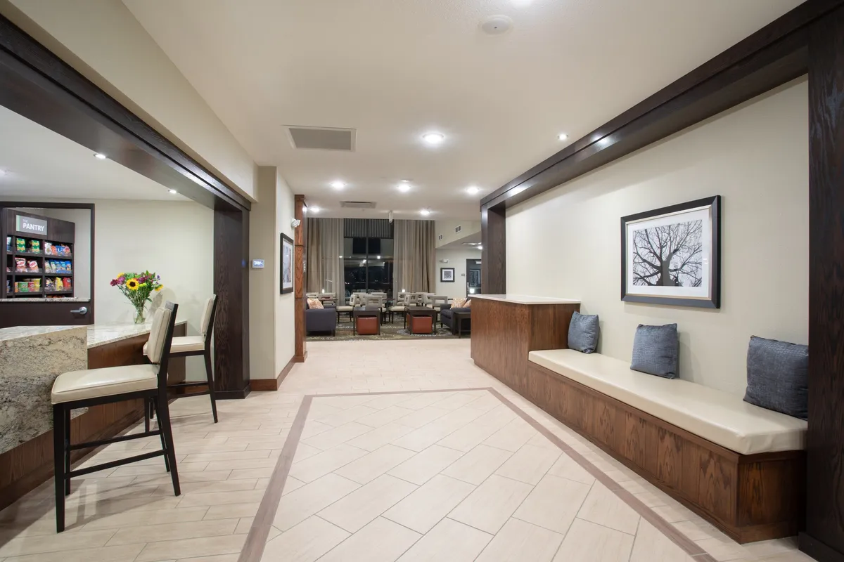 A comfortable and inviting suite interior featuring a granite countertop, cozy seating area, vibrant artwork on the wall, and a fresh sunflower arrangement. The layout is open and flexible, accommodating both relaxation and social interaction.