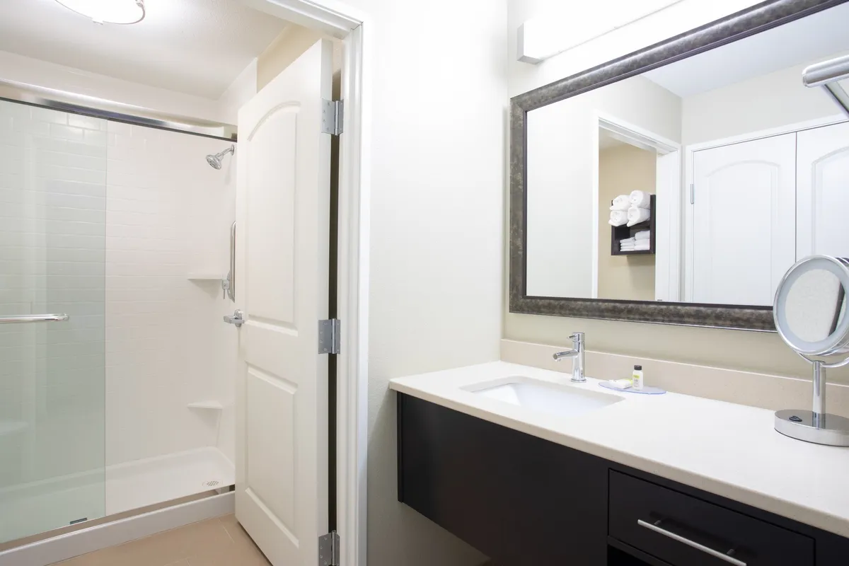 A modern bathroom with a glass-enclosed shower, a stylish vanity with a large mirror, and crisp, clean towels set out for guests. The design is fresh and functional, ideal for quick morning routines or unwinding after a long day.